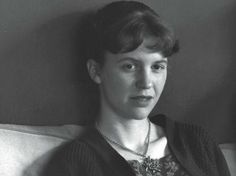 black and white photograph of a woman sitting on a couch with a necklace around her neck