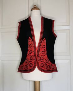 Beautiful wool waistcoat with red applications. Very nice details. The model is slightly fitted and therefore looks very nice. Measurements measured only: Shoulder: 40cm Armpit: 50cm Waist: 46cm Hip: 54cm Length 60cm Depending on the desired fit, it is best suited for size M or L Fitted Red Sweater Vest For Winter, Traditional Fitted Fall Vest, Traditional Fitted Vest For Fall, Red Wool Vest For Winter, Fitted Wool Sweater Vest In Vintage Style, Fitted Wool Sleeveless Sweater Vest, Elegant Embroidered Fitted Vest, Fitted Sleeveless Wool Sweater Vest, Elegant Fitted Embroidered Vest