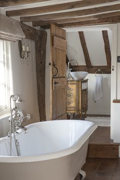 an old fashioned bathtub is in the middle of a room with exposed wood beams