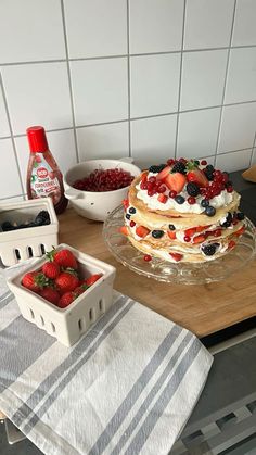 a cake sitting on top of a wooden table next to bowls of berries and yogurt