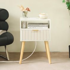 a white table with some books and a cup on it next to a black chair