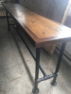 a wooden table sitting on top of a metal frame in a room filled with windows