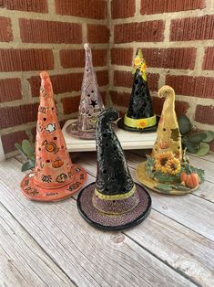 three witches hats sitting on top of a wooden table next to a brick wall and pumpkins