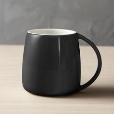 a black mug sitting on top of a wooden table