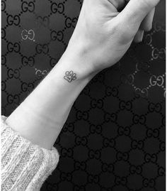 a woman's wrist with a small flower tattoo on the left side of her arm