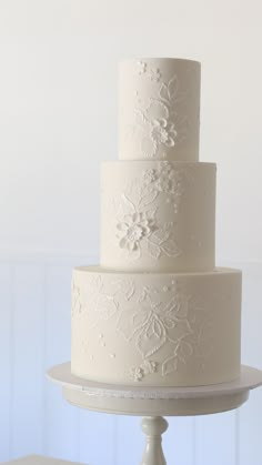 a three tiered white wedding cake sitting on top of a table