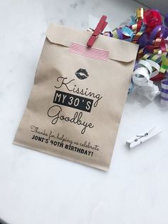 a paper bag that says kissing my 30's goodbye on it next to scissors and confetti