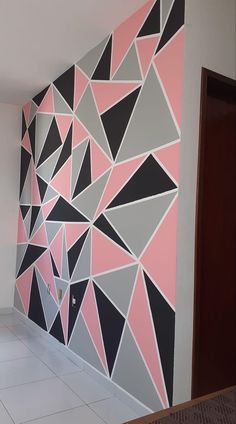 the wall is decorated with black, pink and grey geometric shapes in an empty room