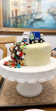 there is a cake on the table with many candies around it and a toy truck on top