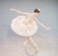 a young ballerina is dressed in pink and white