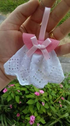 a hand holding a small pink and white piece of cloth with a bow on it