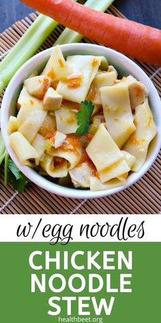 chicken noodle stew in a bowl with carrots and celery on the side