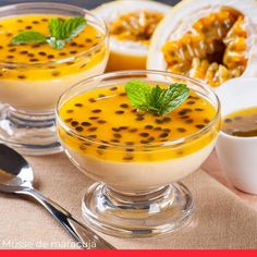 two glasses filled with pudding on top of a wooden cutting board next to spoons