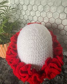 a crocheted white and red hat with ruffles