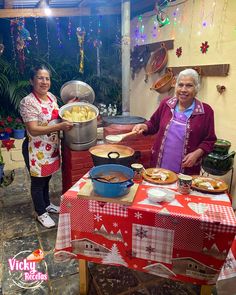 two women standing in front of a table with food on it