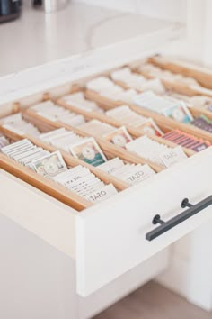 a drawer filled with lots of stamps on top of a white counter next to a wall