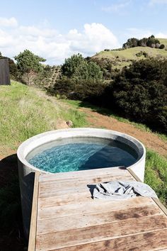 a hot tub sitting on top of a wooden platform next to a lush green field