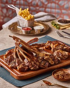 a wooden cutting board topped with meat and french fries