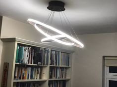 a light that is hanging from the ceiling above a book shelf in a living room