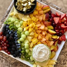 a platter filled with fruit and cheese on top of a table