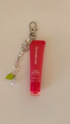 a pink tube sitting on top of a keychain next to a green leaf