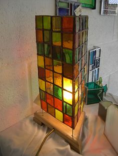 a lamp made out of stained glass blocks sitting on top of a white sheet covered table