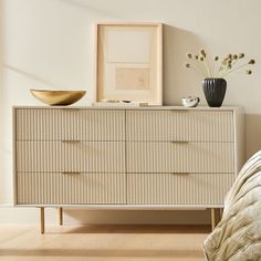 a white dresser sitting next to a bed in a bedroom