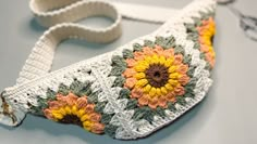 a crocheted purse with sunflowers on the front and side, sitting on a table