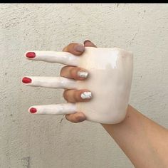 a woman's hand with red and white nails holding a coffee mug