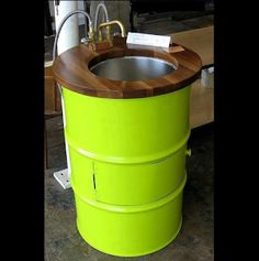 a green barrel sink sitting on top of a counter next to a wooden table and chair