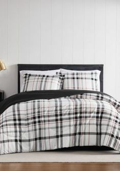 a black and white plaid comforter set on a bed in a room with wood flooring