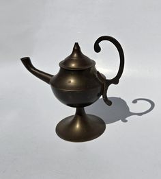 an antique teapot is sitting on a white surface with a shadow from the top