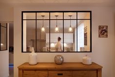 a wooden table topped with vases next to a window filled with light bulb lights