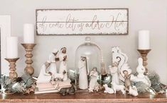 a mantle with candles and figurines on it in front of a christmas sign