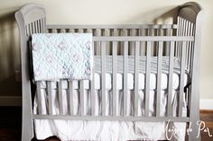 a baby crib with white bedding and a blue blanket on the top of it