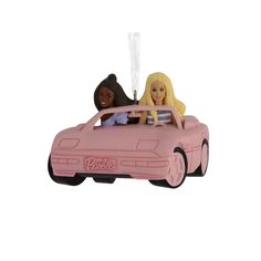 a pink car ornament with two barbie dolls in it