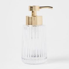 a clear glass soap dispenser with a gold faucet