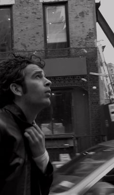 black and white photograph of a man in front of a building looking up at the sky