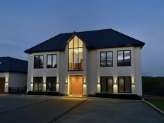 a large white house with black shutters and lights on the front door at night