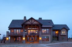 a large brown house with lots of windows and lights on it's front porch