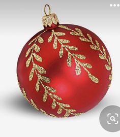 a red ornament with gold leaves on it's side and a white background