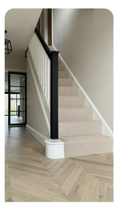 an empty staircase leading up to the second floor with white carpet and black handrails