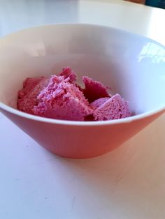 a bowl filled with pink ice cream on top of a table