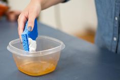 a person is cleaning the table with a blue sponge and a plastic container on it