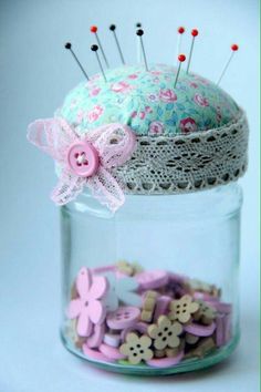 a jar filled with buttons and pins sitting on top of a table