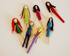 six dolls are lined up on toothpicks in the shape of people with long hair