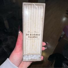 a person holding up a birthday candle in a box with the number 24 on it