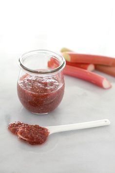 a jar filled with red sauce next to some carrots and celery sticks