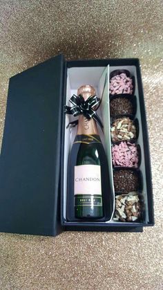 a bottle of champagne and some chocolates in a black box on the floor next to it