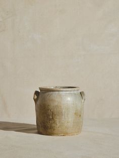 a white vase sitting on top of a table next to a beige wall and floor